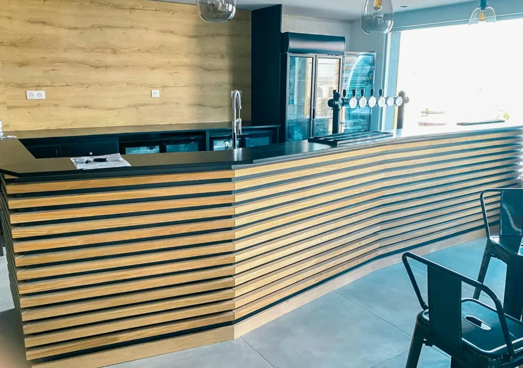 Comptoir de bar sur mesure réalisé par Vivet Agencement avec habillage en tasseaux de bois.